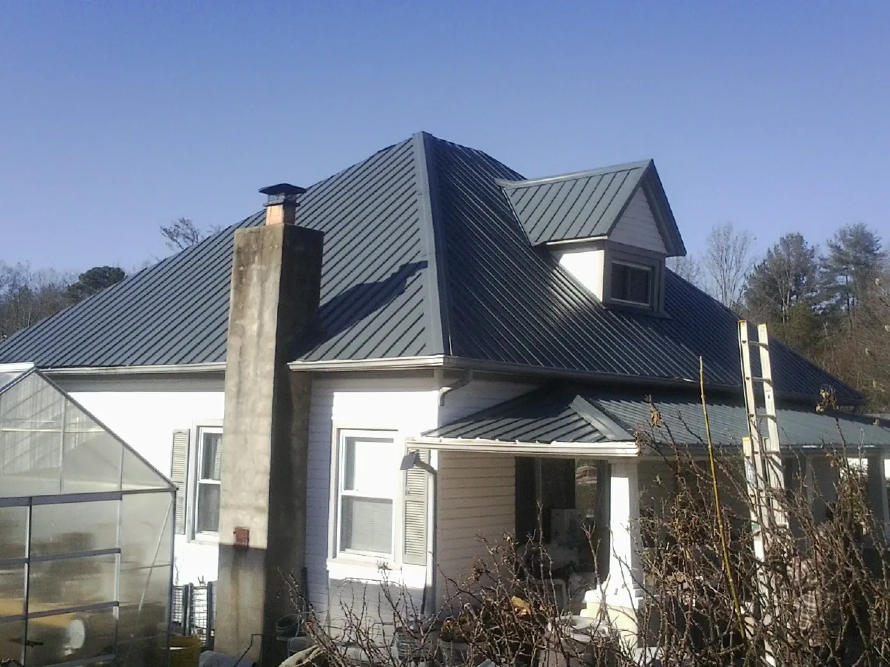 Dark blue standing seam metal roof on a white farmhouse with dormer — Slate & Tile Roof Repair by Roofing Brothers in Snoqualmie