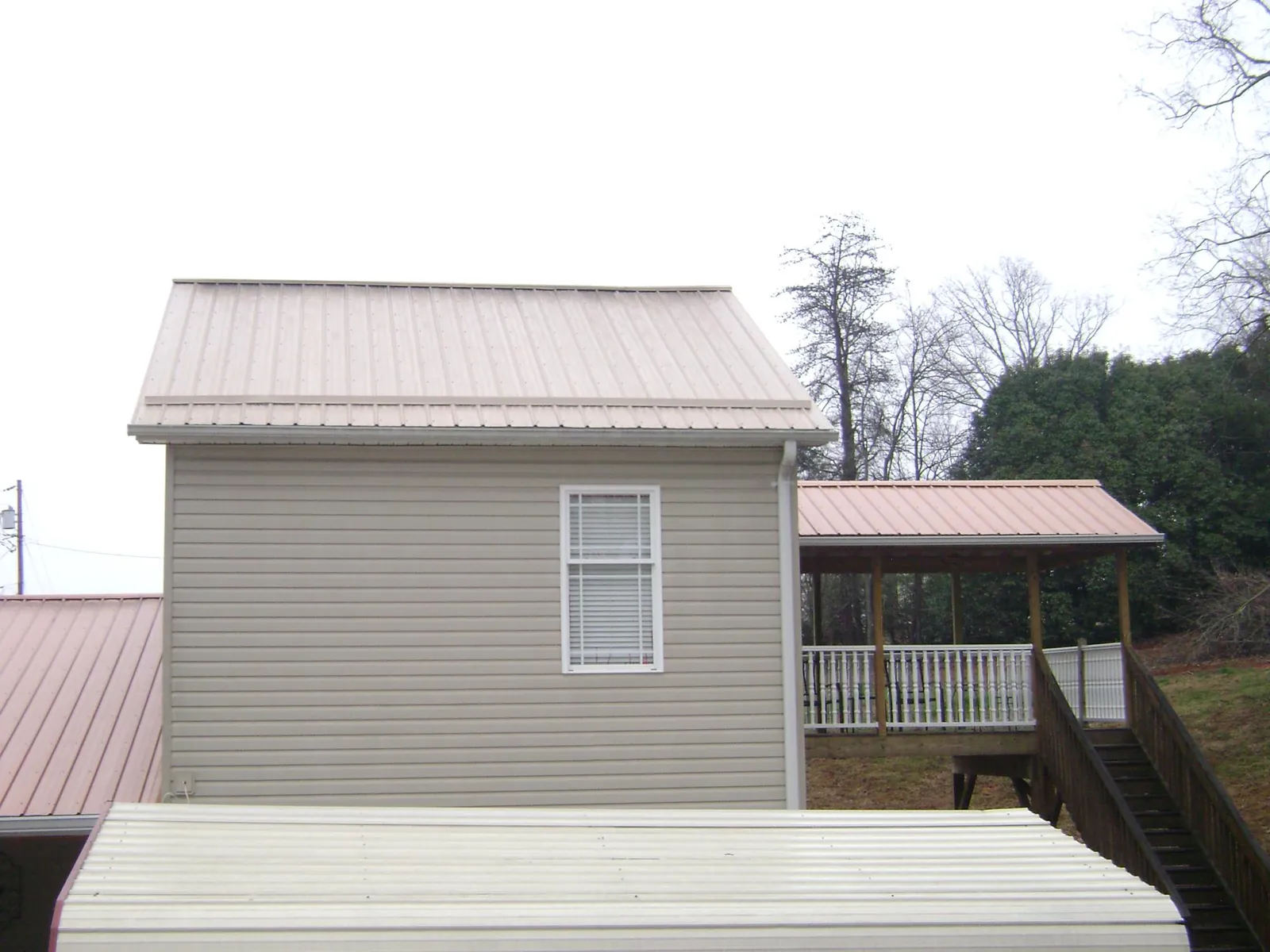Tan metal roofs on a two story addition and attached porch, from a Roof Replacement job in Snoqualmie