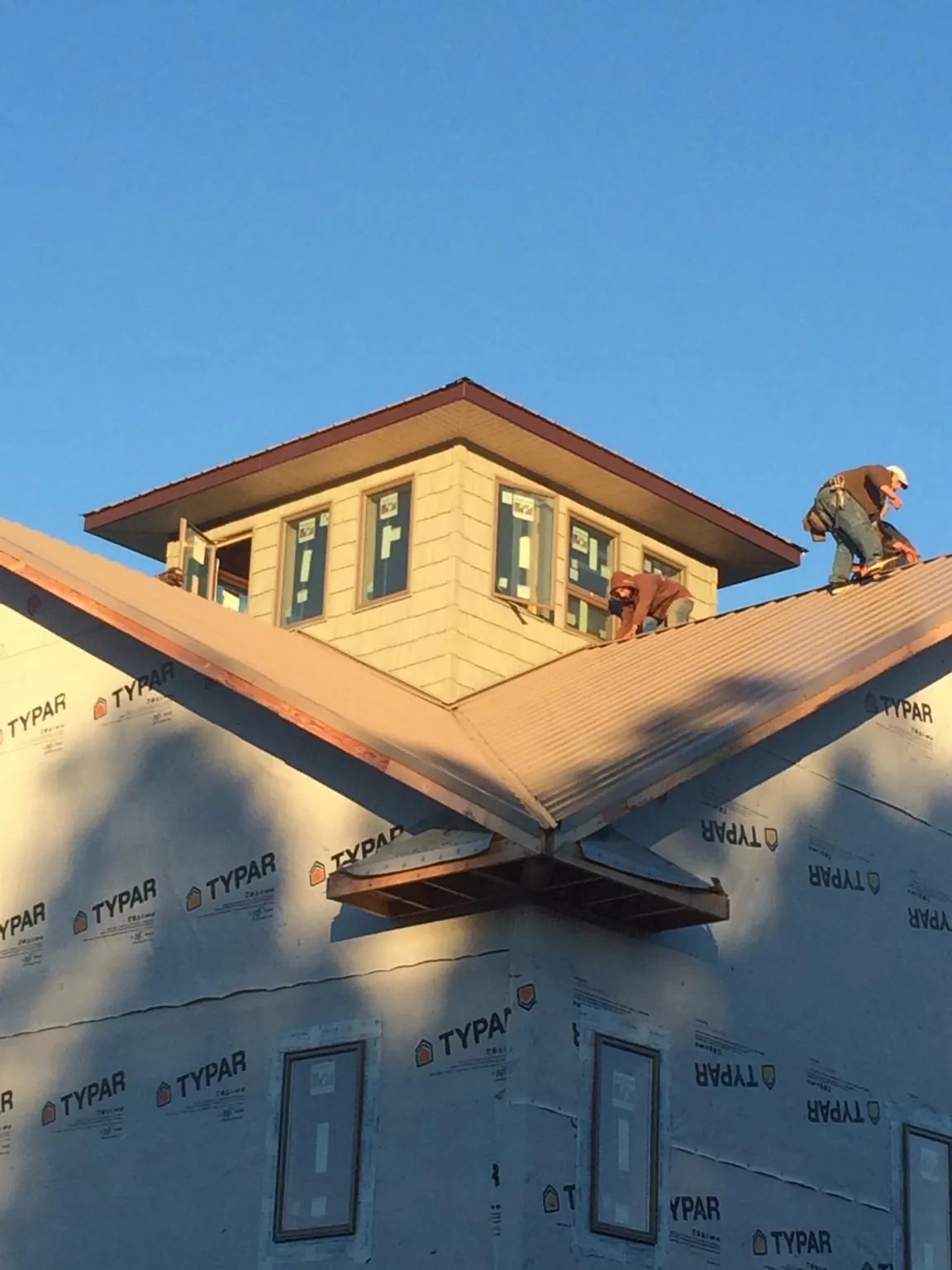 Roofers working around a rooftop cupola on a new metal roof at sunset — Roof Waterproofing in Snoqualmie by Roofing Brothers